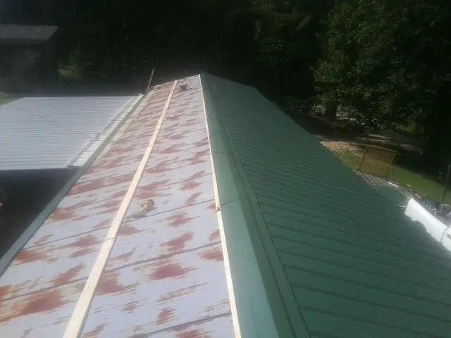 Old rusted panels beside newly installed green metal roofing — Wind Damage Roof Repair by Roofing Brothers in Fort Rock
