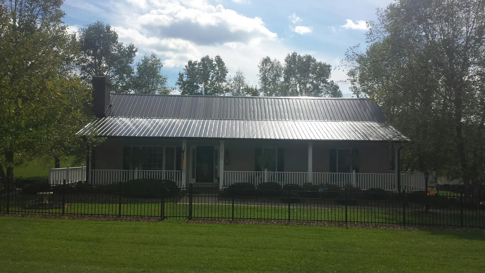 Gray metal roof on a brick ranch with a full width front porch — Gutter Guard Installation work by our crew in Fort Rock