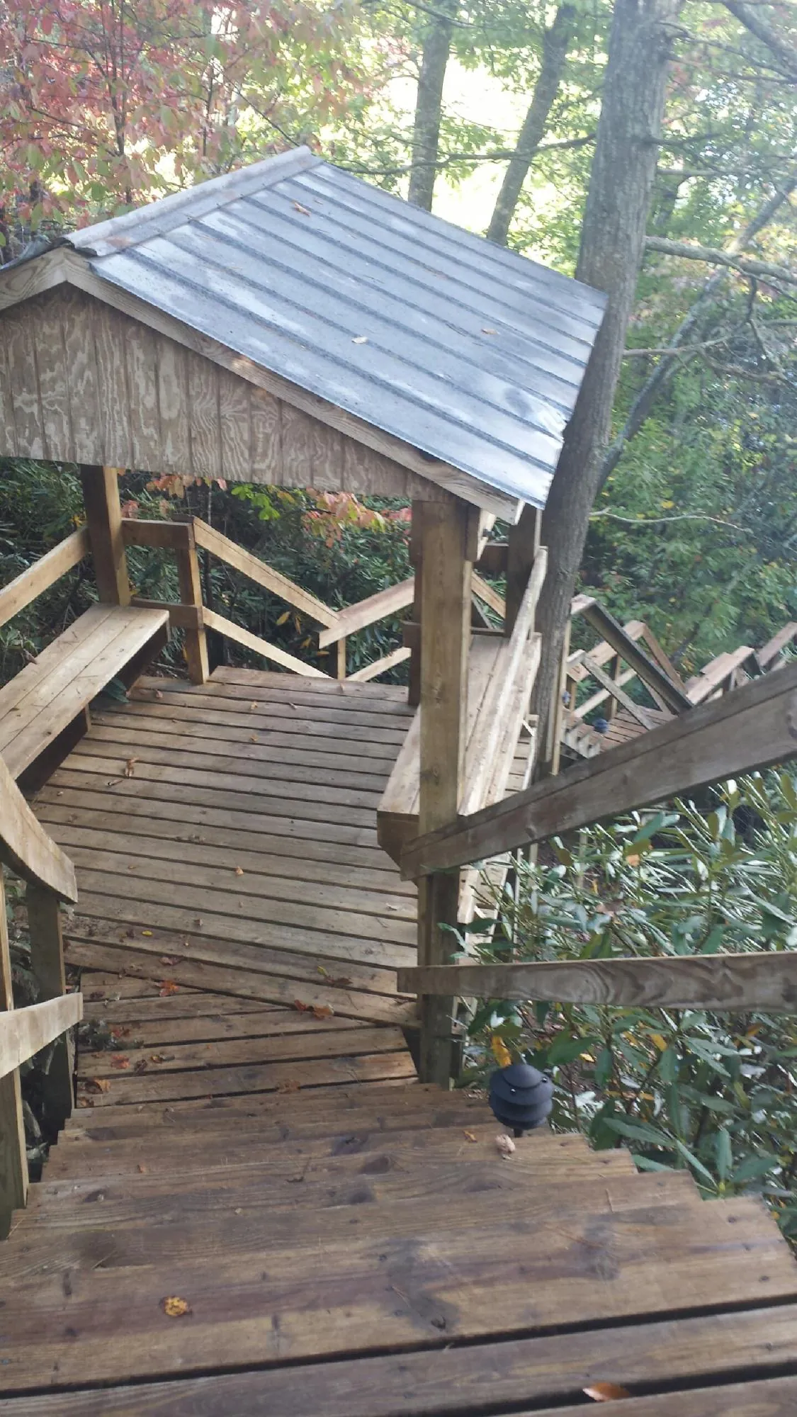 Metal roofed shelter over wooden steps on a wooded walkway — Skylight Repair & Installation work by our crew in Fort Rock