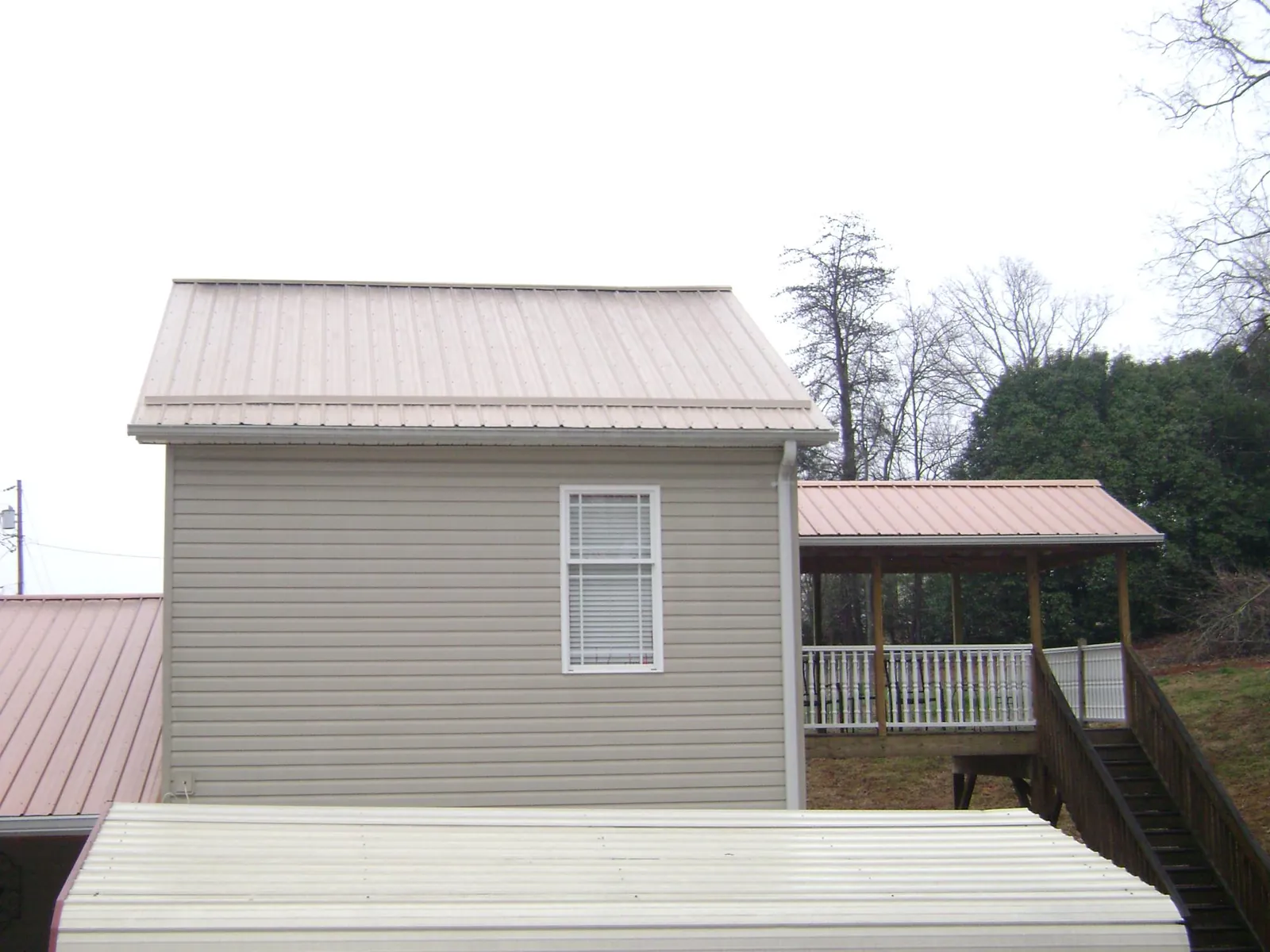 Tan metal roofs on a two story addition and attached porch, from a Roof Replacement job in Fort Rock
