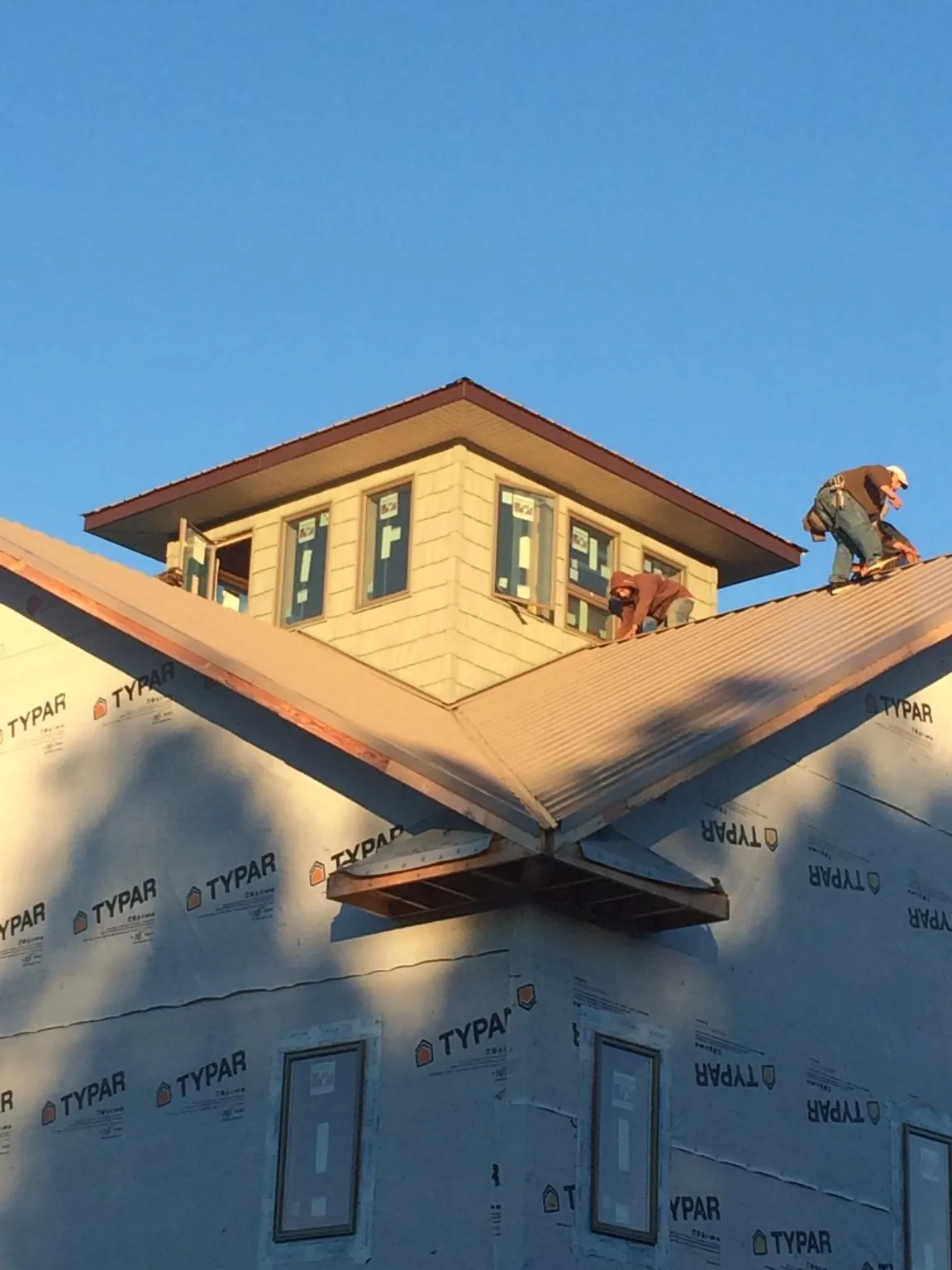 Roofers working around a rooftop cupola on a new metal roof at sunset — Roof Waterproofing in Fort Rock by Roofing Brothers